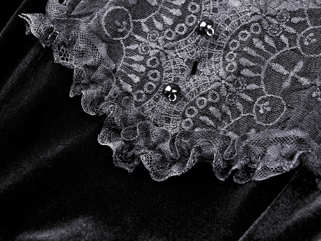 Detailed view of black velvet fabric with ornate lace panel and decorative buttons on gothic dress