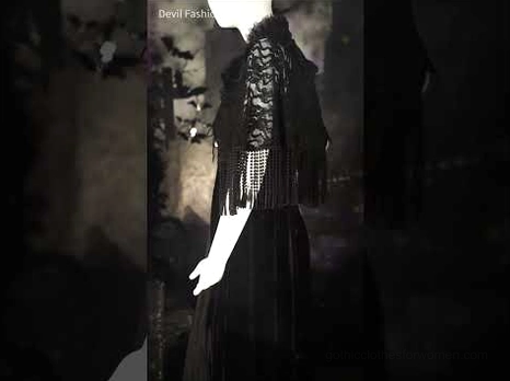 Gothic lace-trimmed black velvet maxi dress with off-shoulder neckline and decorative lace sleeve shawl with tassel details, partial figure view in dim dark studio lighting