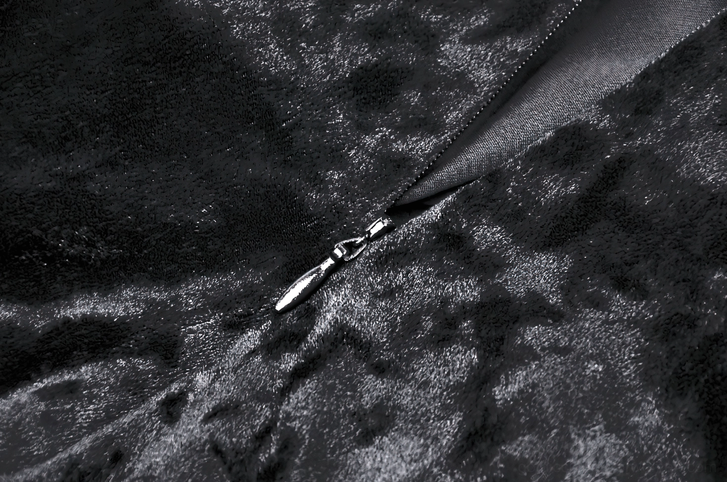 Close-up detail of black velvet dress front metal zipper closure with satin zipper tape