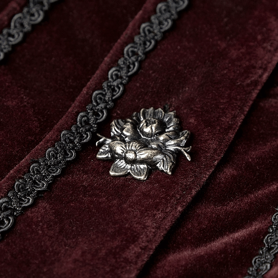 Close-up detail of wine-red velvet fabric with carved bronze metal flower button and braided trim embellishment