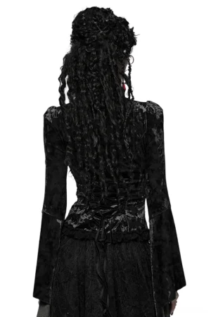 Back full-body view showing lace-up corset back closure and dramatic flared sleeves of gothic velvet lace top, model with dreadlocks