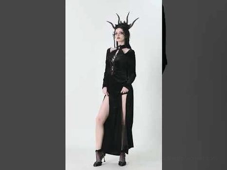 Three-quarter side view of gothic velvet maxi dress on model with horned headdress, showing fitted silhouette and high side slit