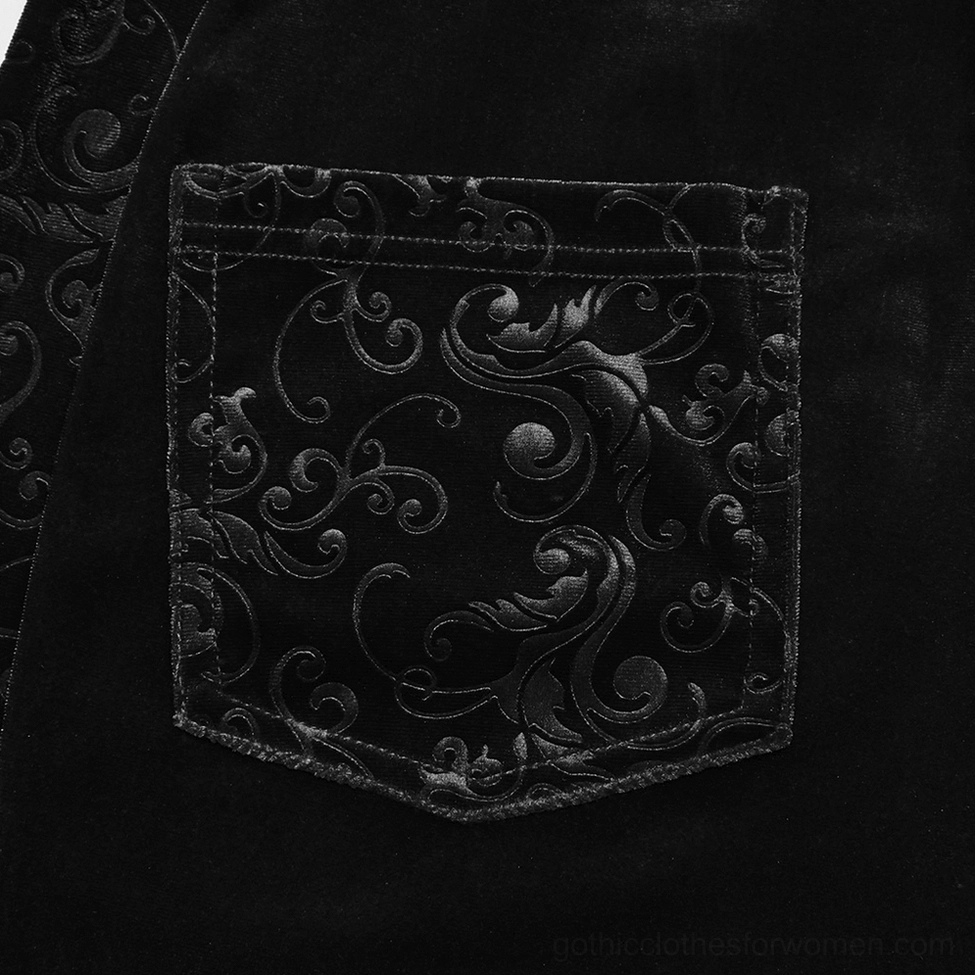 Close-up detail of black gothic velvet pants showing scroll and baroque embossed pattern on fabric