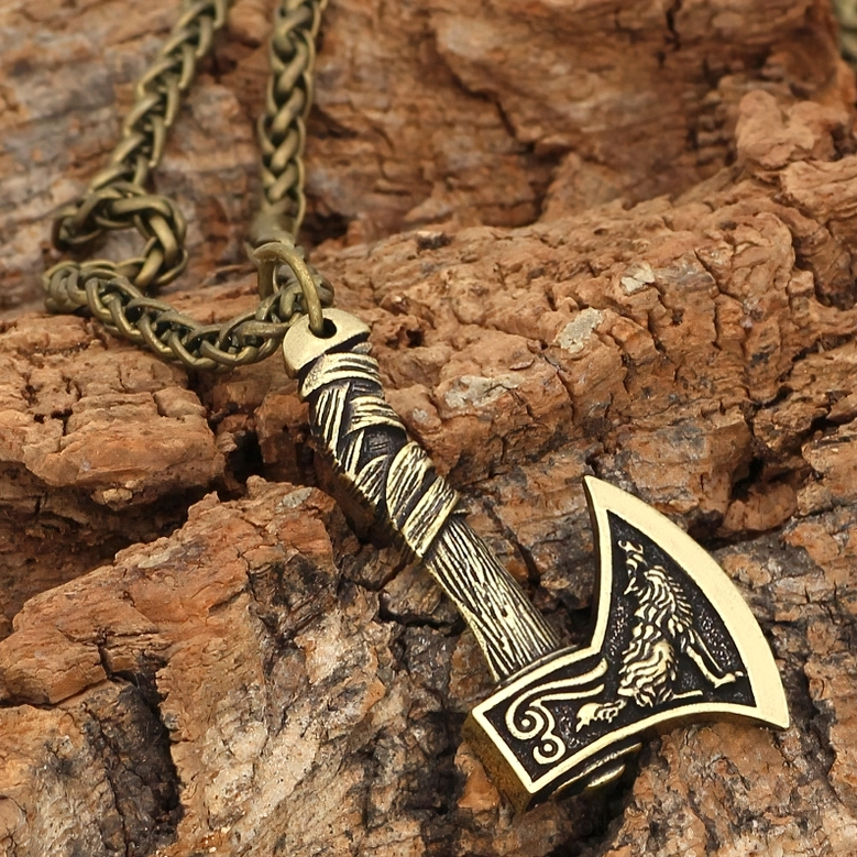 Bronze wolf-patterned Viking axe pendant on brass chain with natural bark background
