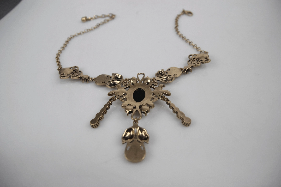 Vintage gothic pendant with ornate metal frame and central dark gemstone, dangling charm detail top-down view