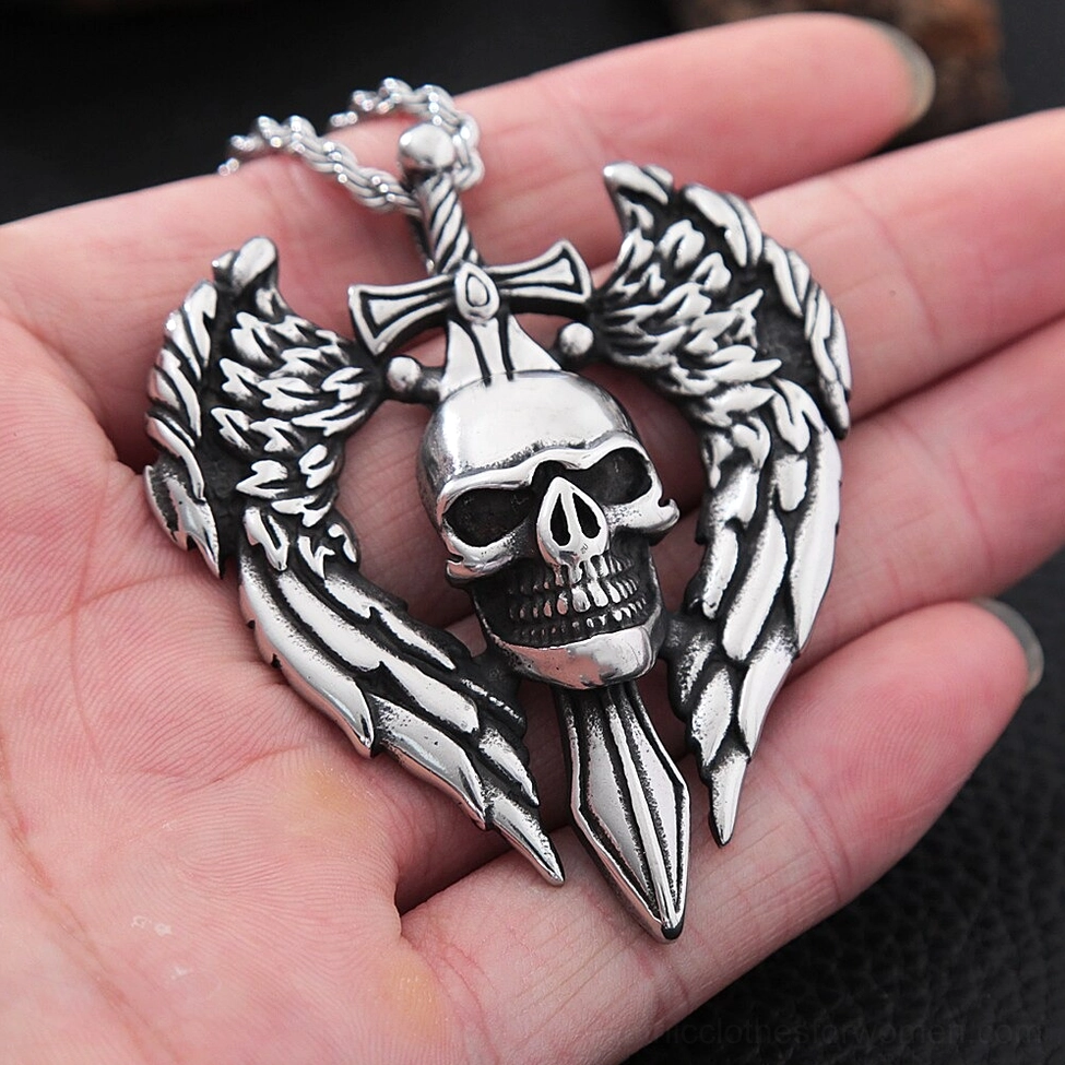 Winged skull pendant necklace held in human palm, first-person wear view on dark surface showing scale and wearability