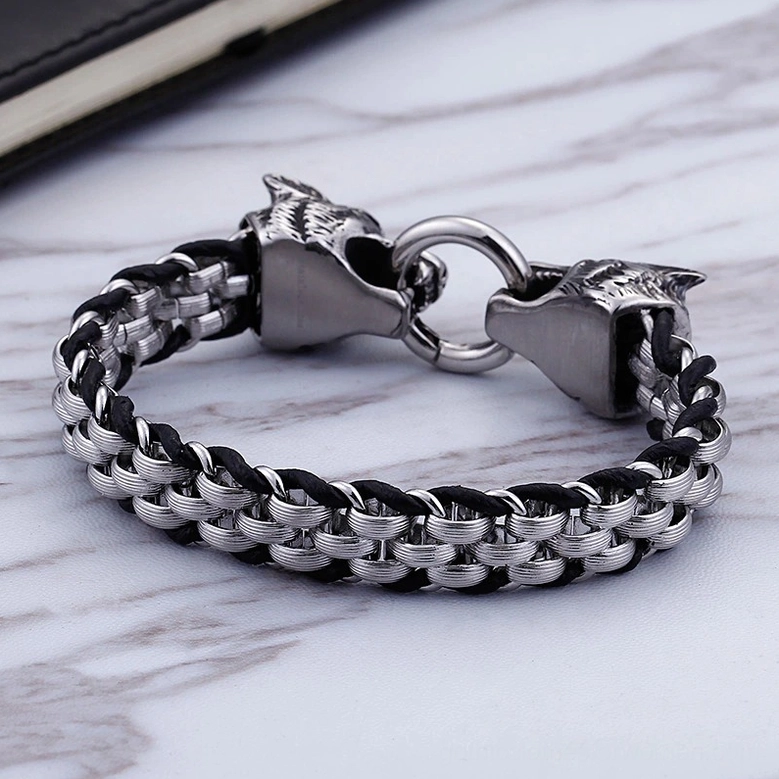 Overhead view of gothic wolf head bracelet displayed on marble surface with notebook, showing woven metal-leather construction