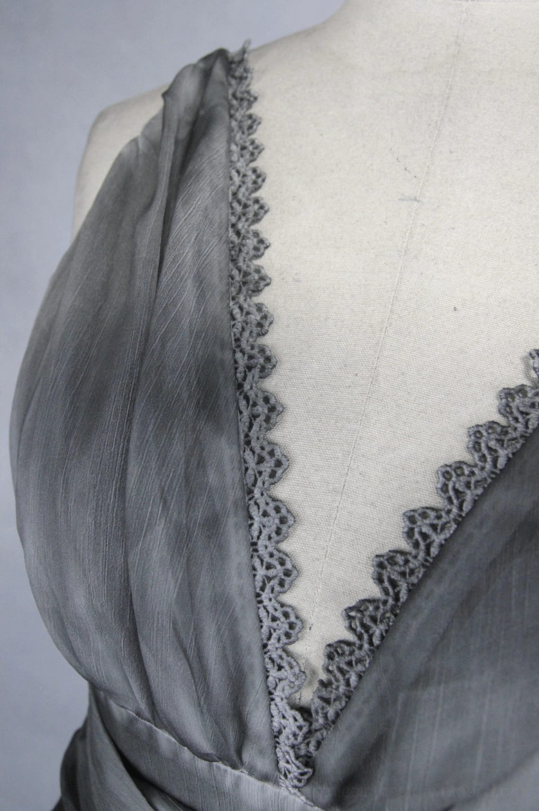 Side close-up of grey dress neckline with lace edging and draped chiffon silk fabric detail
