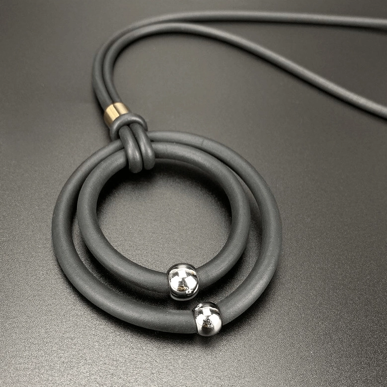 Grey gothic rubber cord necklace with dual round pendants and silver accent beads close-up flat lay