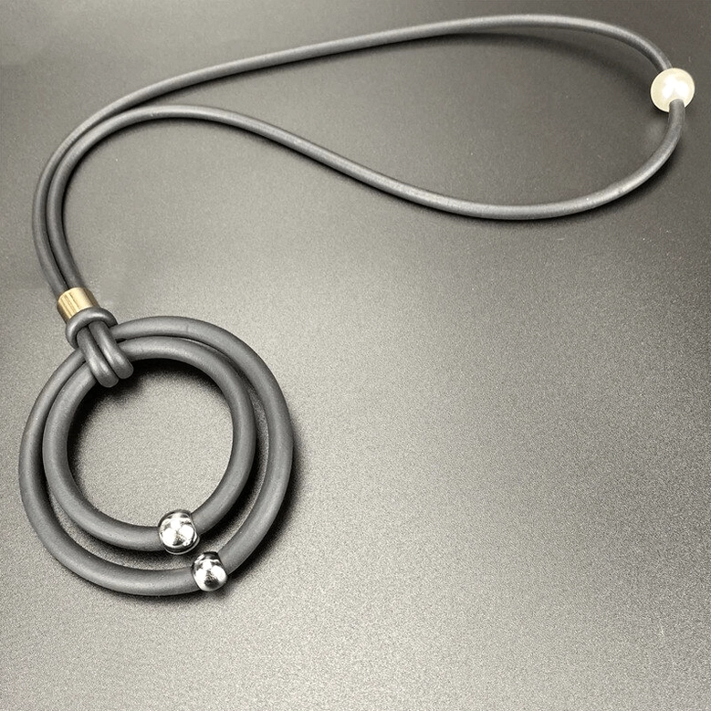 Grey gothic pendant necklace with silver metal beads and matte grey rubber cord angled flat lay view