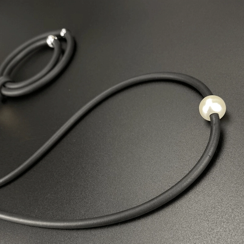 Grey gothic necklace with white faux pearl pendant displayed on dark grey background flat lay