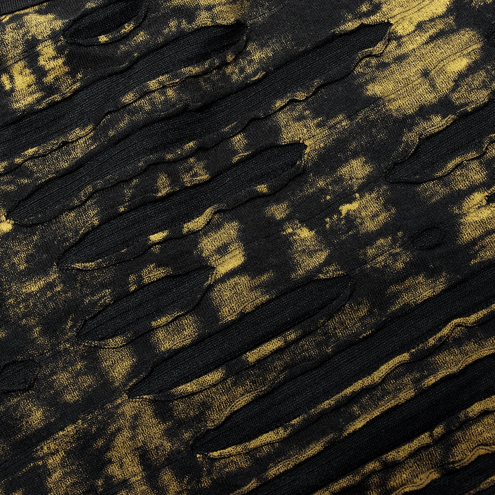 Close-up of black and yellow tie-dye distressed knit fabric pattern