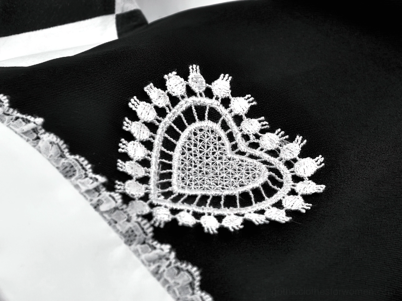 Close-up macro detail of harlequin jester hat showing delicate white lace heart embroidery and trim