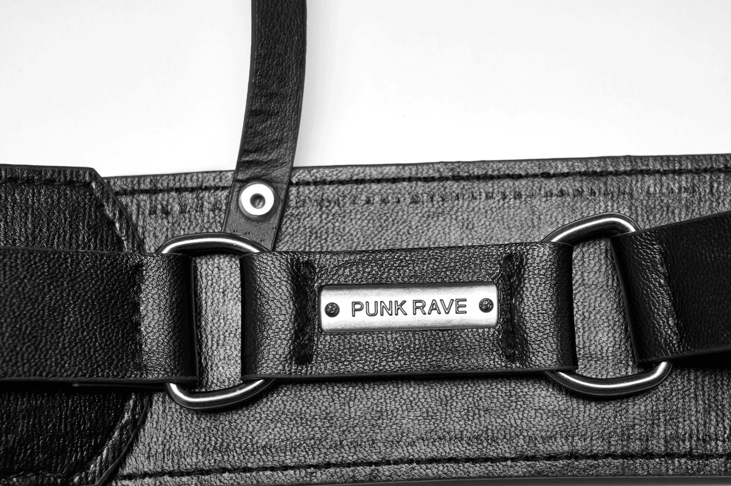 Black gothic harness close-up detail shot, metal D-rings and punk nameplate branding, PU leather texture and hardware