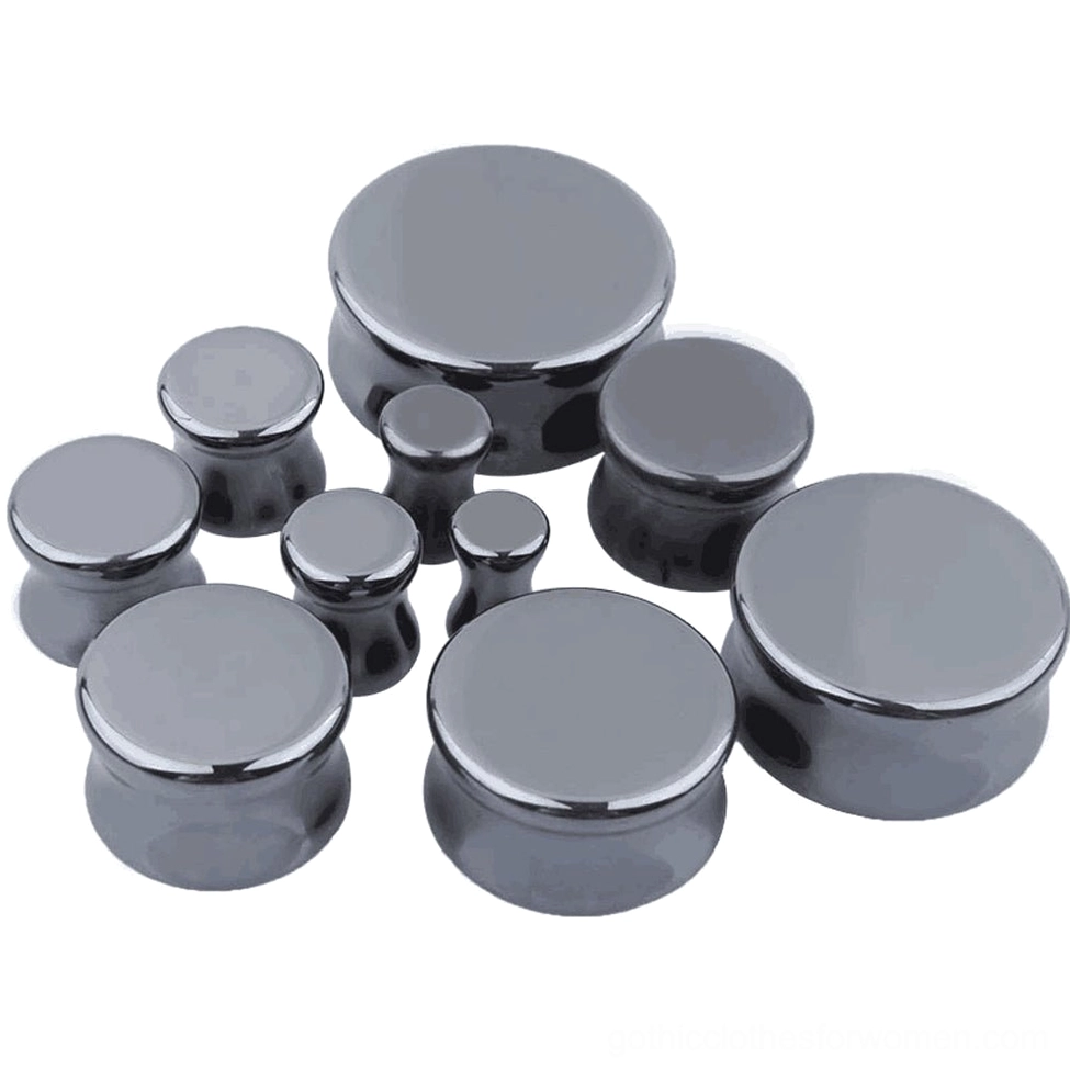 Multiple hematite stone ear expander plugs in different gauges from 6mm to 25mm, overhead flat lay showing size progression and gunmetal gray finish