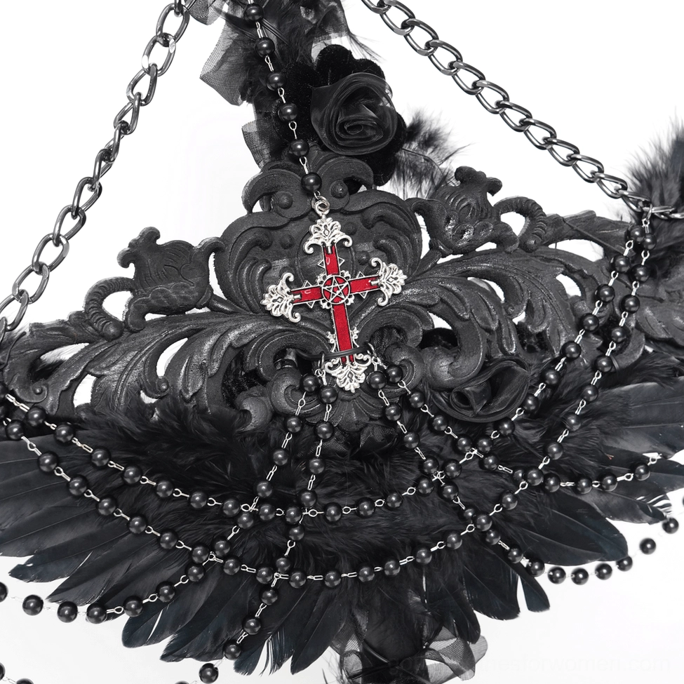 Overhead top-down close-up of inverted cross ornament showing intricate metal carved details and feather trims