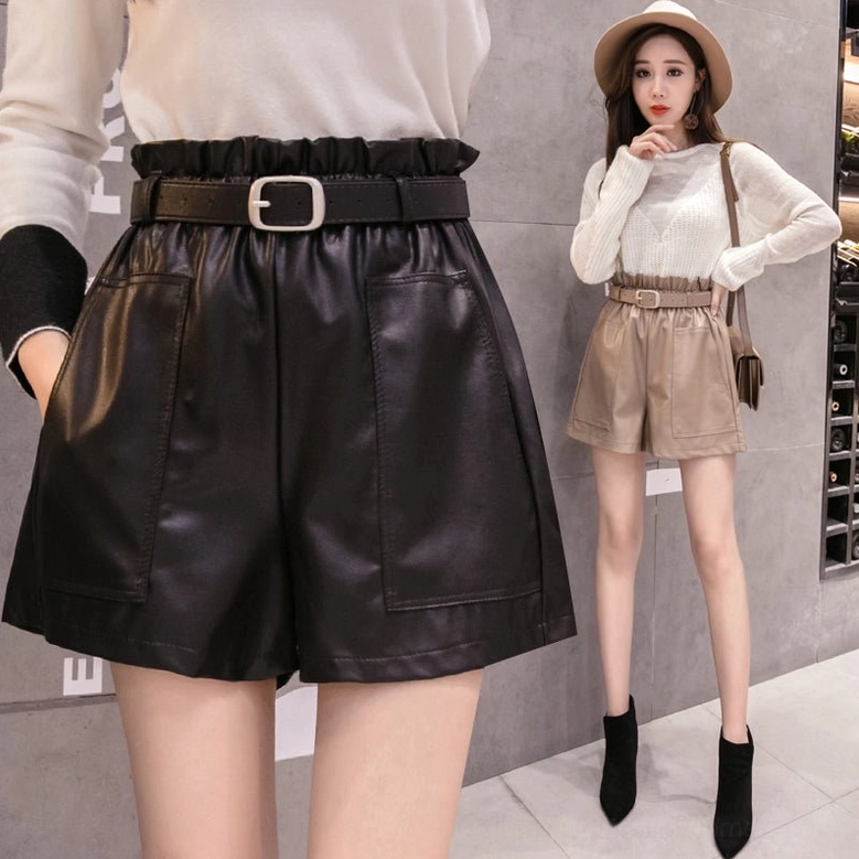 Khaki faux leather high-waist wide-leg shorts worn by model in cellar setting, full body front view with crossbody bag