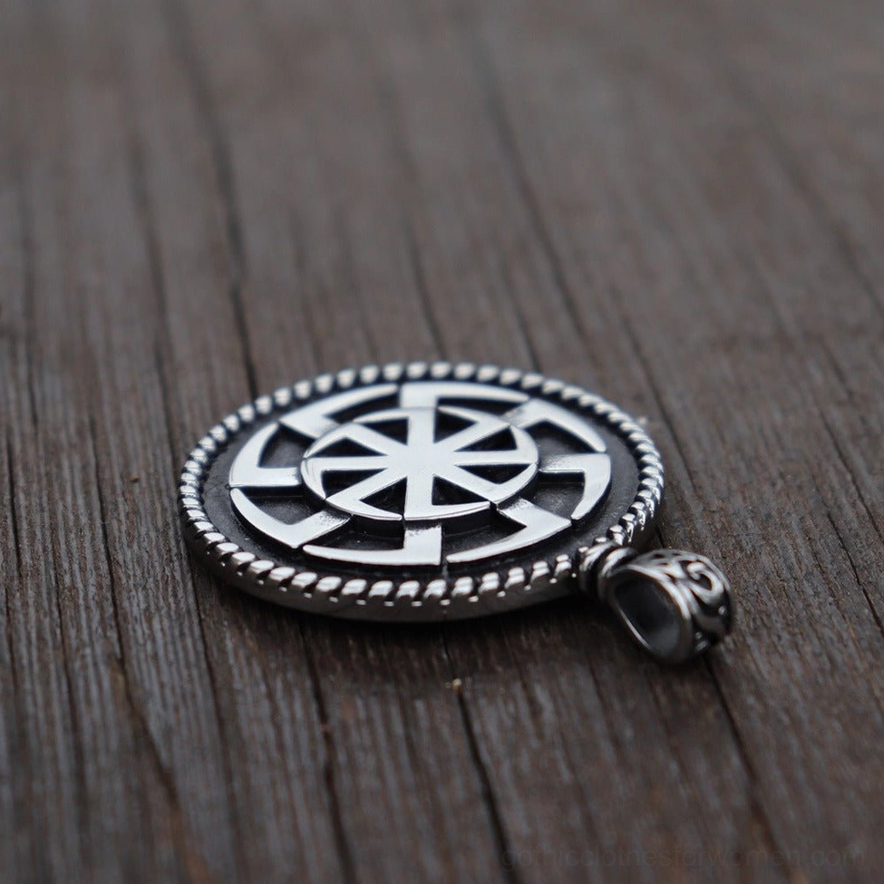 Kolovrat sun wheel pendant top-down flat lay - intricate wheel pattern detail visible