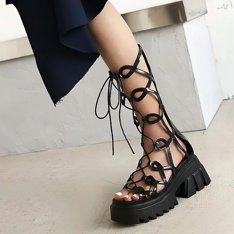 Black platform sandals close-up showing circular cutout lace strap detail and serrated sole