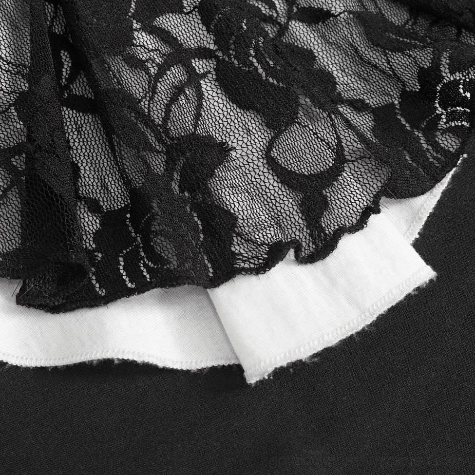 Close-up detail of black floral lace trim with ruffled edge on white cotton fabric base of gothic blouse