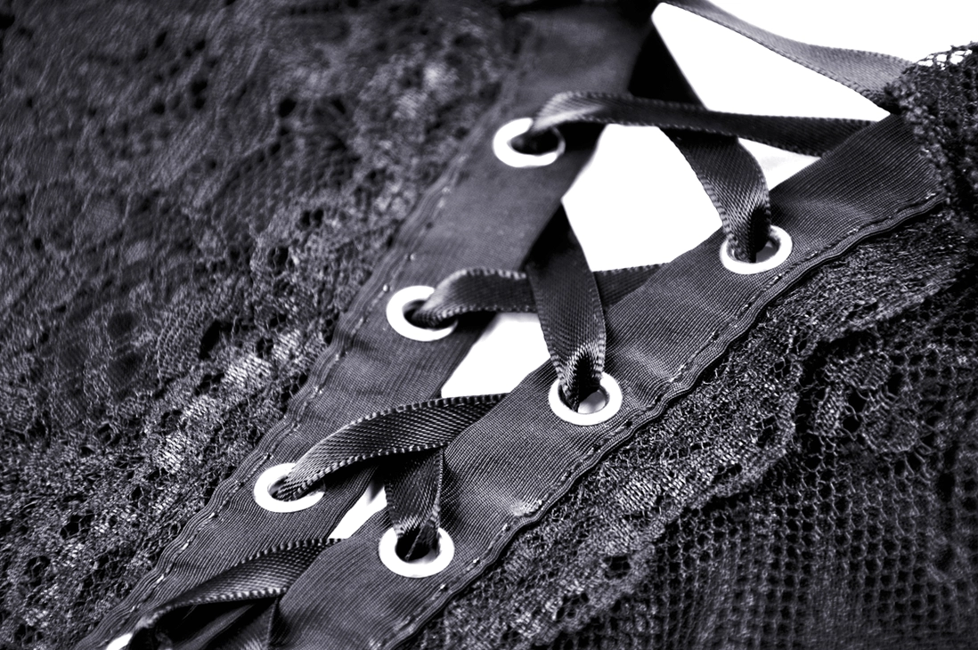 Close-up detail of satin ribbon lace-up closure with metal eyelets on black gothic dress
