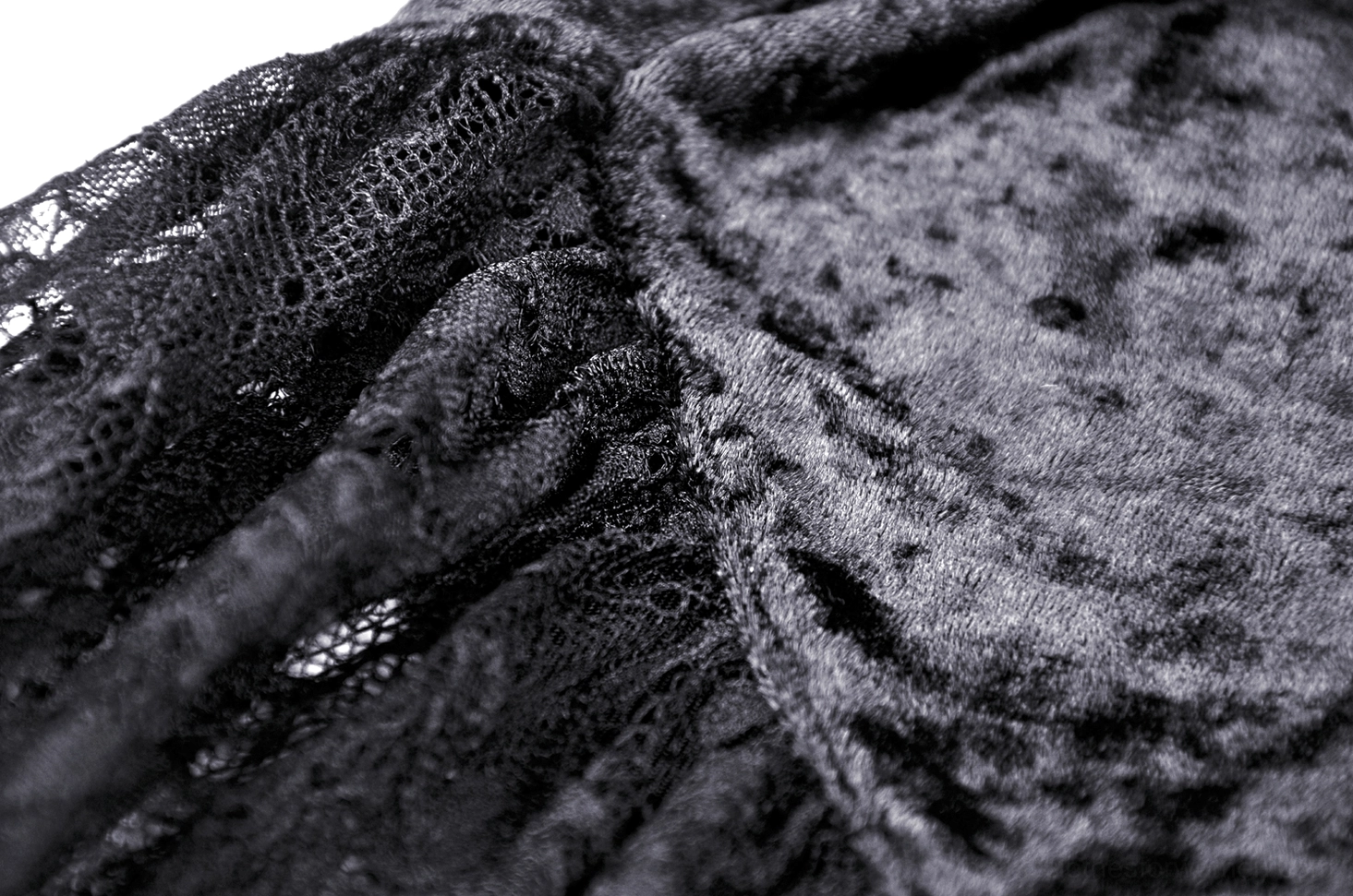 Lace and velvet fabric combination close-up, black lace overlay on velvet with seamless stitching