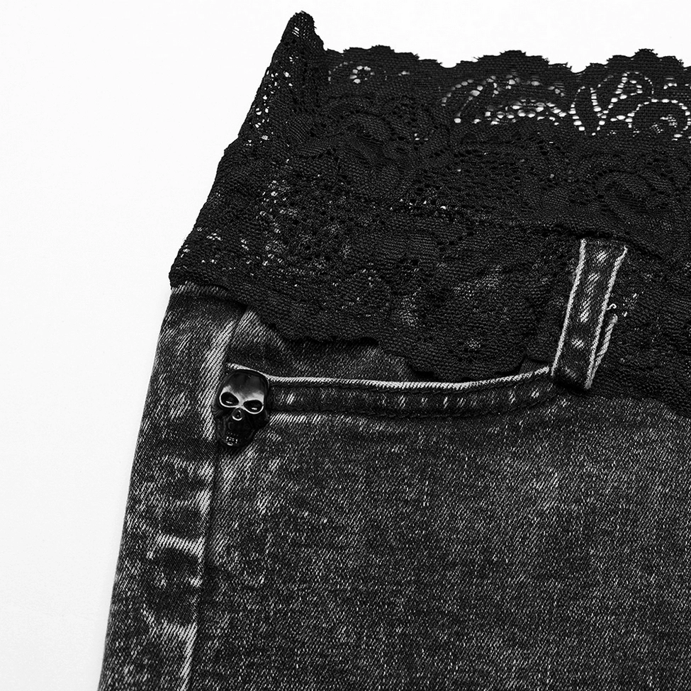 Detailed close-up of scalloped black lace waistband trim with skull-shaped denim button and belt loops on gothic shorts