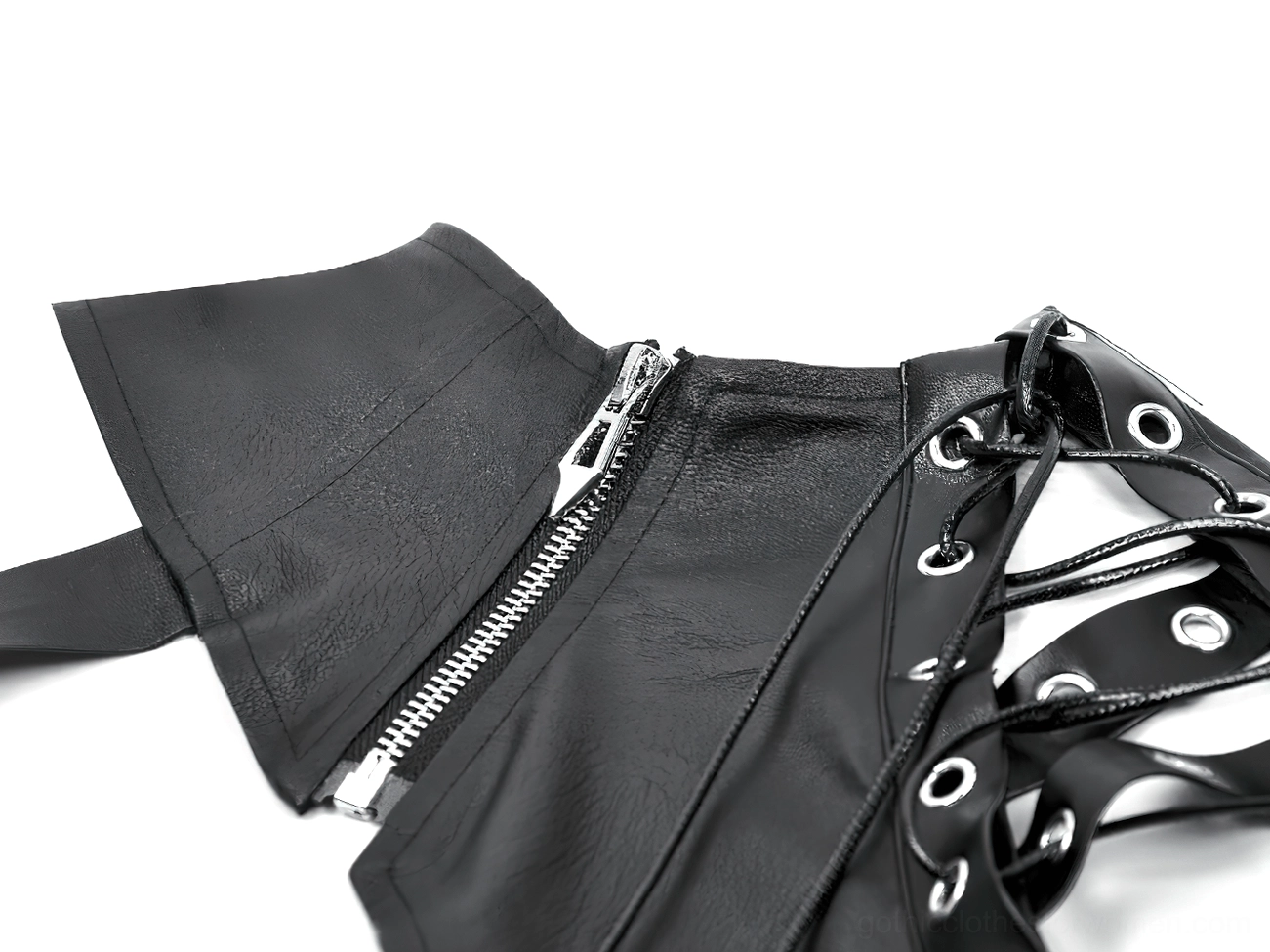 Flat lay macro detail shot showing metal hardware, lace-up eyelets, and matte black leather texture of shoulder cape