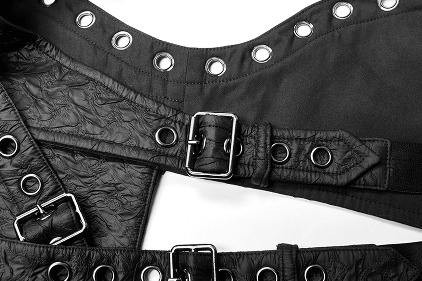 Close-up detail of metal buckles, round eyelets, and textured faux leather composite on gothic body harness