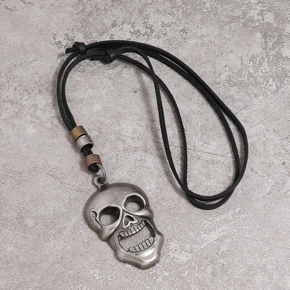 Punk gothic skull necklace flat lay, showing black leather strap with multi-tone metal accent beads on concrete background