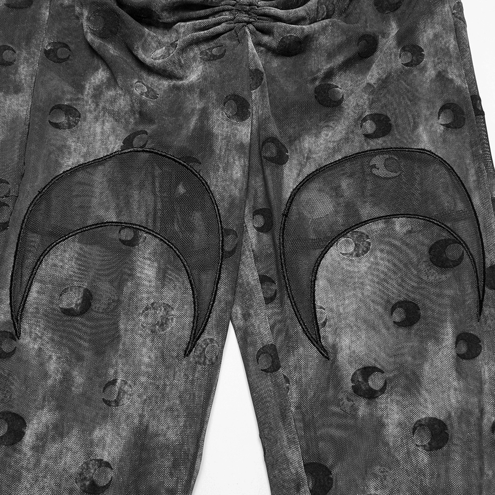 Textile detail shot highlighting sheer mesh fabric composition and crescent moon embroidery pattern of gothic pants