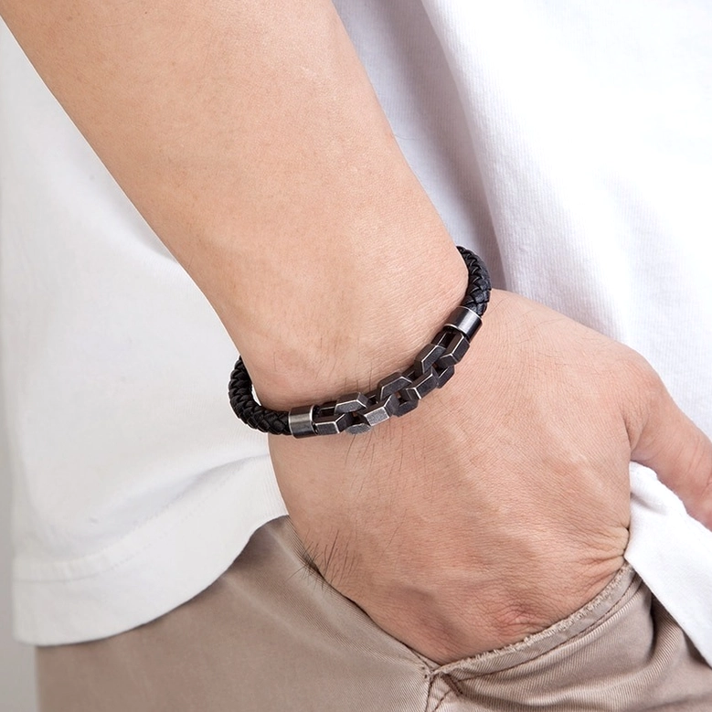 Man wearing black leather and gunmetal chain gothic bracelet on wrist, lifestyle close-up showing real-world wear