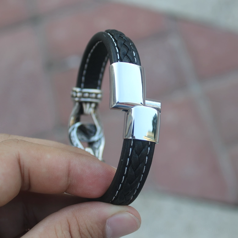 Profile view of black braided leather bracelet with magnetic snap clasp, tiled indoor background
