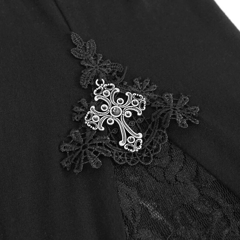 Close-up product detail of metal cross ornament decoration on black fabric base with surrounding lace trim on gothic leggings