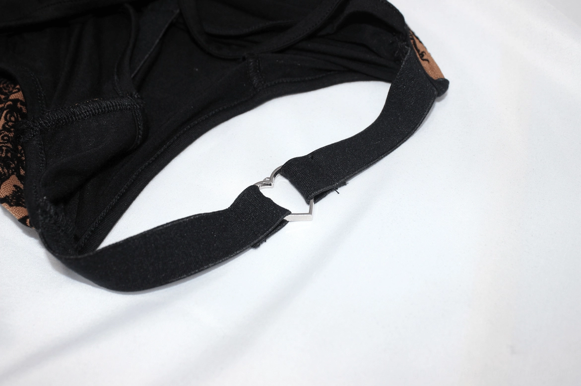 Metal heart buckle hardware on black elastic strap - close-up detail of dress strap fastener