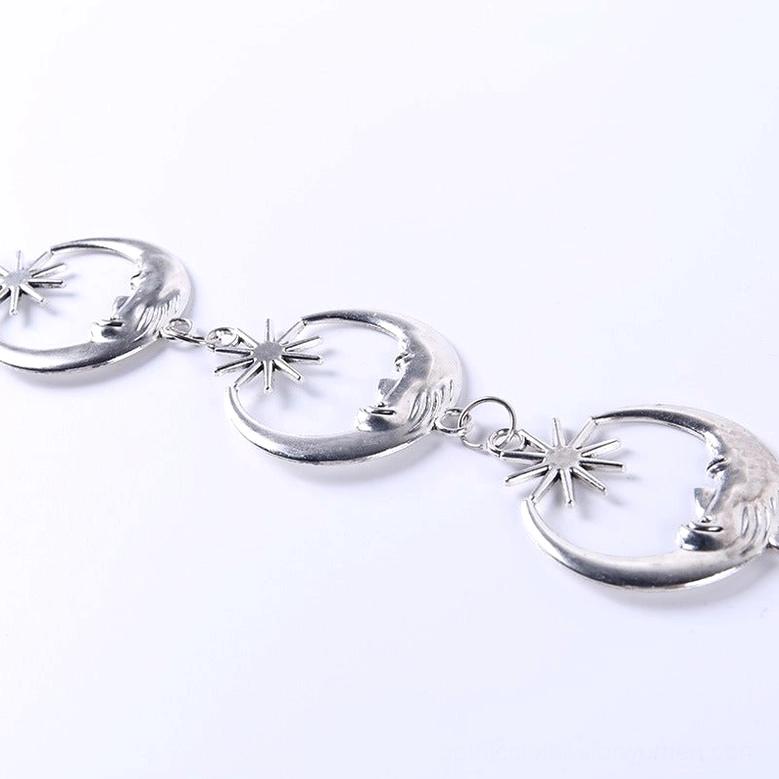Top-down flat lay close-up of crescent moon and star metal links in silver-tone gothic chain belt
