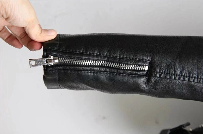 Black faux leather jacket front pocket detail with sash decoration and zipper mechanics on PU leather