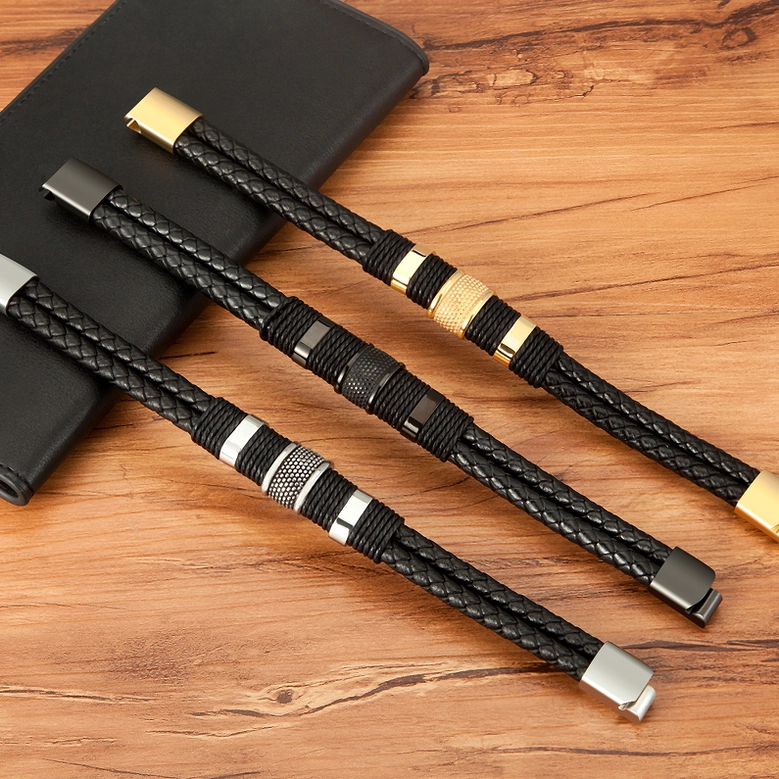 Three men's woven gothic bracelets with multiple hardware finishes - silver, gun-black, and gold on wooden surface