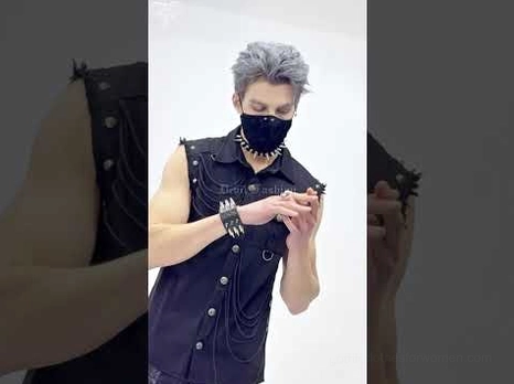 Narrow black spiked leather wristband worn on male model's left wrist, demonstrating compact spike layout and dark fashion styling