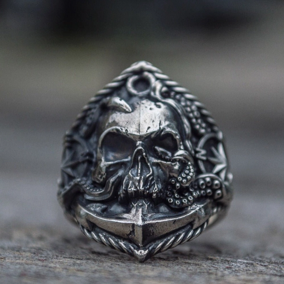 Octopus anchor skull ring with dark silver metal, twisted rope border and skull anchor details on stone surface