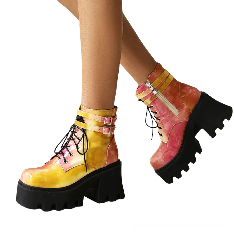 Woman wearing ombre yellow red gothic platform ankle boots with dual buckle straps and chunky lug sole, styled low angle view