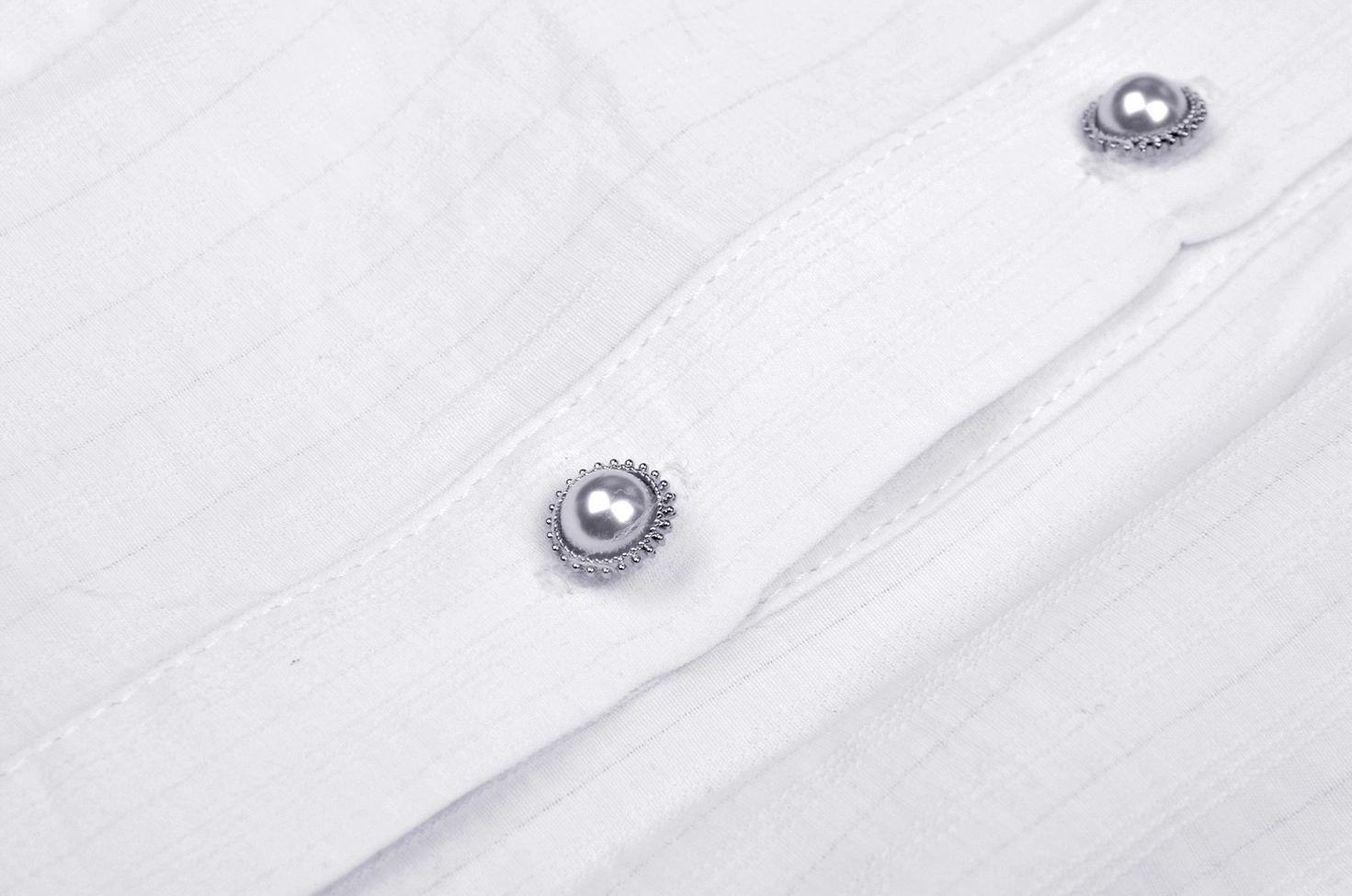 Decorative metal pearl button detail on white lace Victorian blouse with subtle striped texture