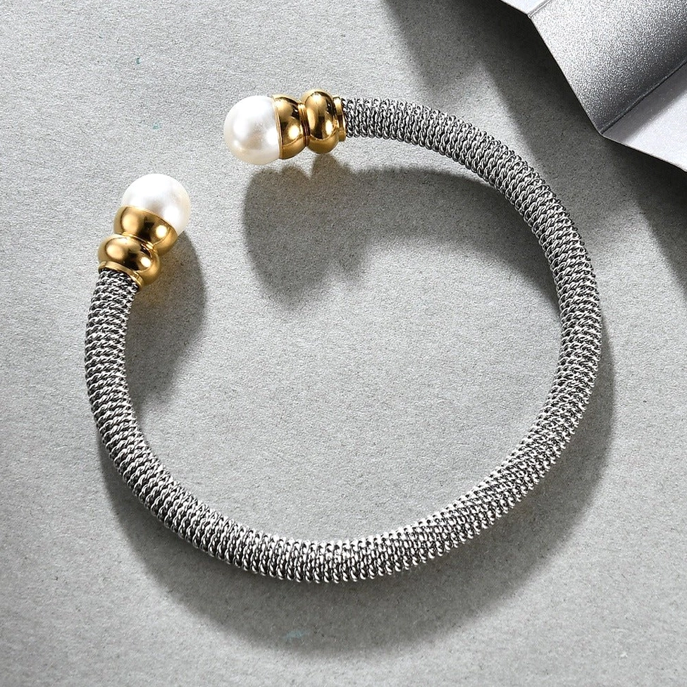 Top-down view of victorian pearl cuff on matte grey background with metal trim styling