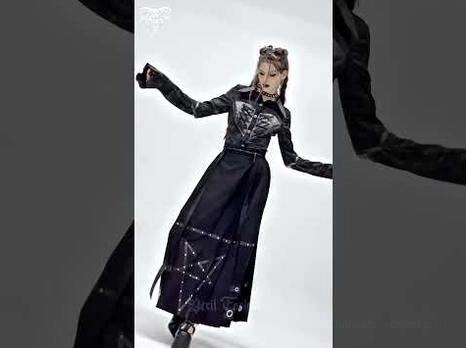 Female goth model wearing black pentagram maxi skirt with matching dark outfit and platform boots in dynamic side pose