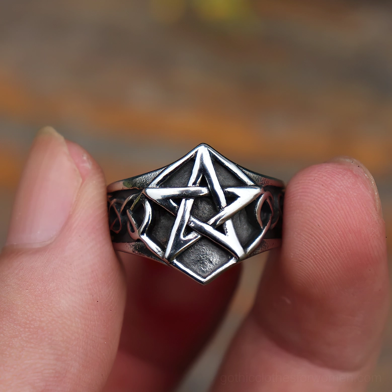 Gothic pentagram stainless steel ring held by two fingers against warm brown background, showcasing vintage finish and dimensional design