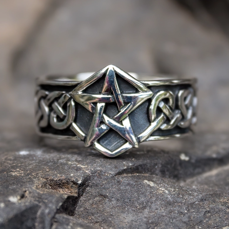 Close-up of pentagram gothic ring with natural stone background, highlighting Celtic trim and polished stainless steel details