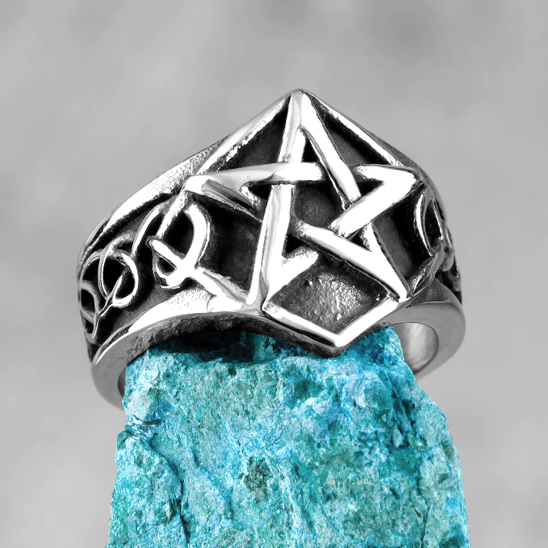 Stainless steel pentagram ring photographed against turquoise stone, emphasizing prominent five-pointed star design