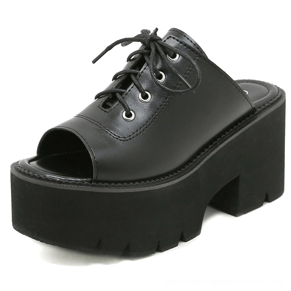 Close-up of metal lace eyelets and polished black leather finish on platform gothic sandal