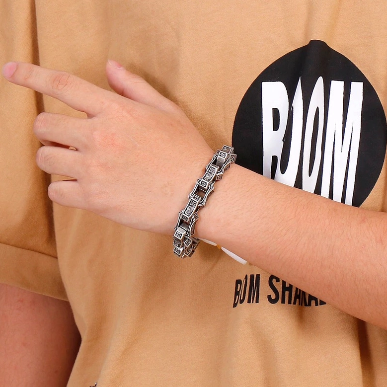 Light silver polished gothic engraved bracelet on male wrist showing detailed carved square links