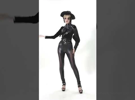 Side profile of gothic punk leather cape outfit with wide brim hat and heeled sandals, complete alternative fashion ensemble
